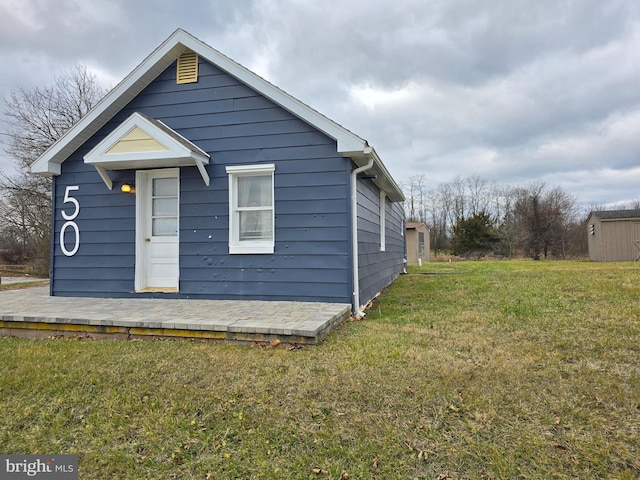 back of house featuring a yard and a storage shed