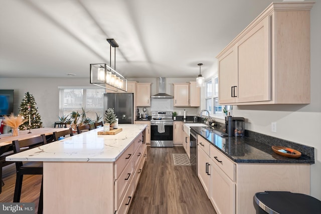 kitchen featuring appliances with stainless steel finishes, a wealth of natural light, pendant lighting, and wall chimney range hood