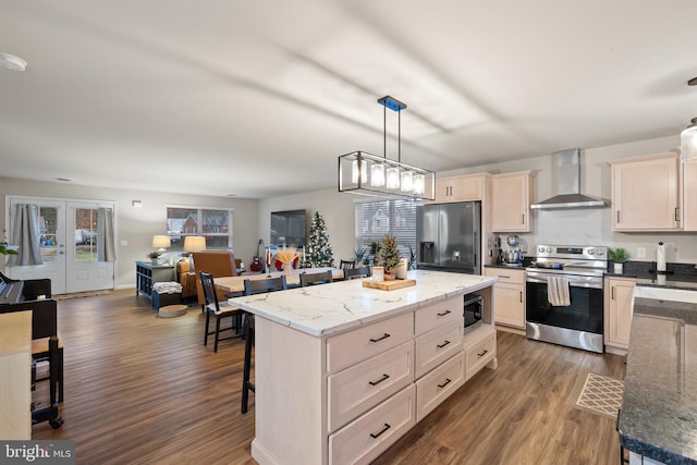 kitchen featuring stainless steel appliances, wall chimney range hood, pendant lighting, a center island, and dark hardwood / wood-style floors