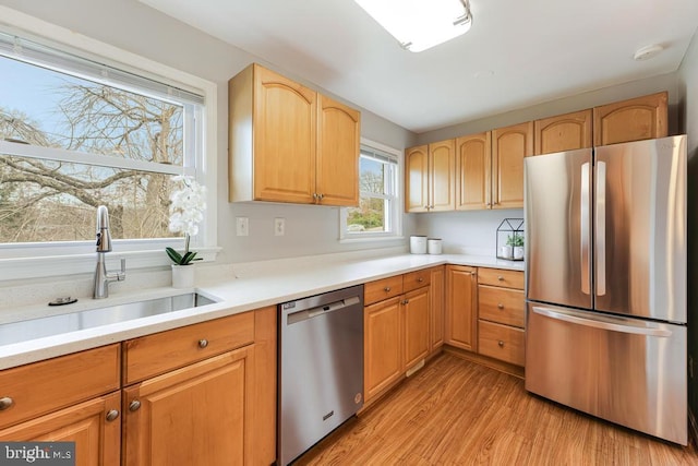 kitchen featuring appliances with stainless steel finishes, light hardwood / wood-style floors, light brown cabinets, and sink