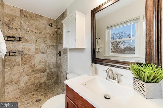 bathroom featuring tiled shower, vanity, and toilet