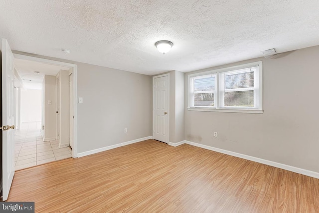 unfurnished room with a textured ceiling and light hardwood / wood-style floors