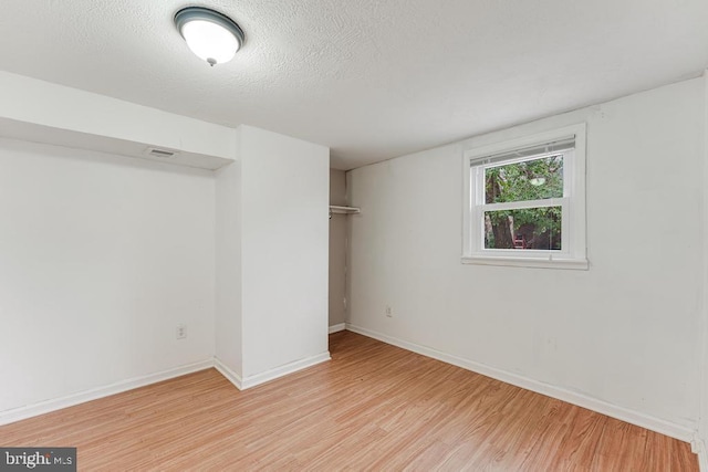 unfurnished room featuring a textured ceiling and light hardwood / wood-style flooring