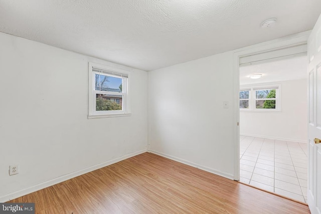 unfurnished room featuring a textured ceiling, light wood-type flooring, and a wealth of natural light