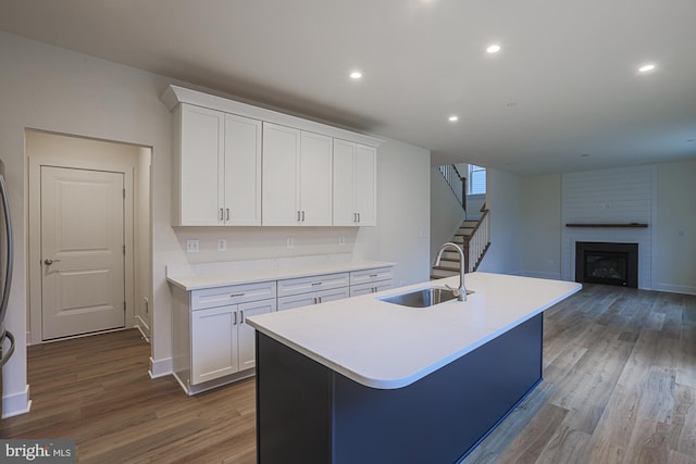 kitchen with a kitchen island with sink, white cabinetry, dark wood-type flooring, and a sink