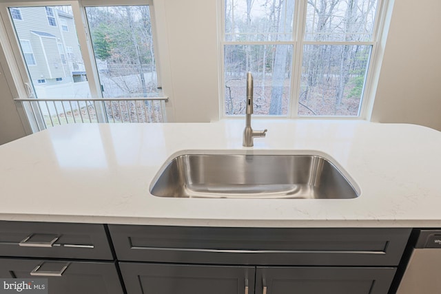 kitchen featuring light countertops, stainless steel dishwasher, and a sink