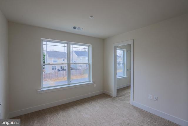 empty room featuring baseboards, visible vents, and light colored carpet