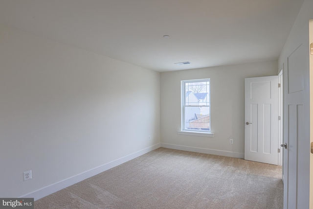 empty room with carpet, visible vents, and baseboards