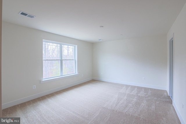 unfurnished room with light carpet, visible vents, and baseboards