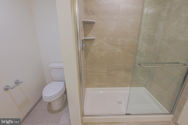 full bath featuring a stall shower, baseboards, toilet, and tile patterned floors