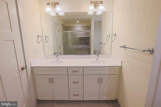 bathroom with double vanity, a stall shower, a sink, and toilet