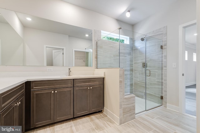 bathroom featuring a shower with door and vanity