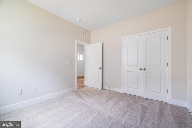 unfurnished bedroom featuring light colored carpet and a closet