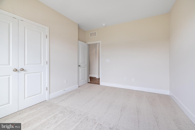 unfurnished bedroom featuring a closet and light colored carpet