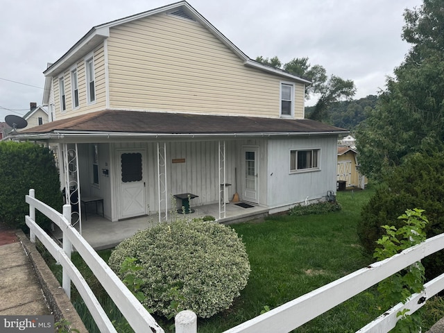 rear view of property featuring a lawn and covered porch