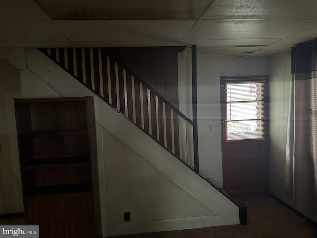 interior space with a paneled ceiling and wood walls