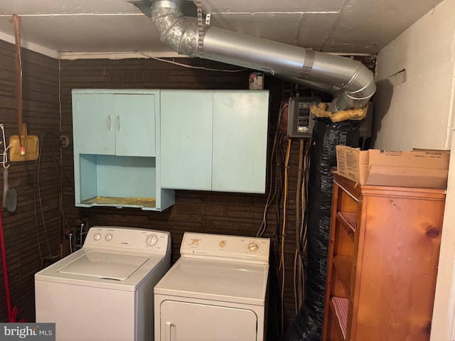 washroom with cabinets, washing machine and dryer, and wooden walls