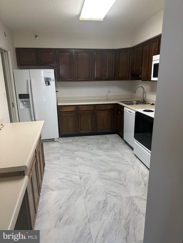 kitchen with dark brown cabinets, sink, and white appliances