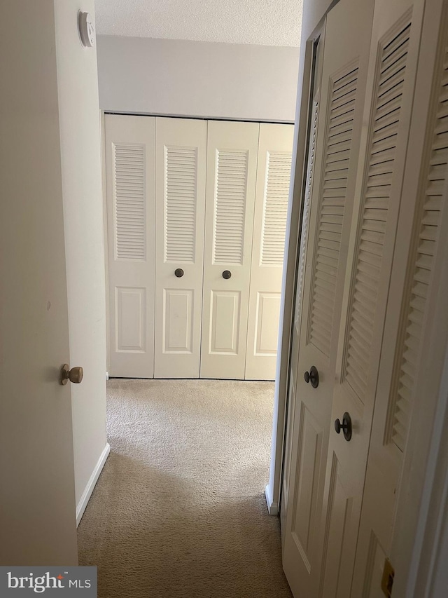 corridor featuring carpet flooring and a textured ceiling