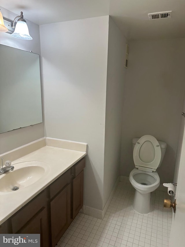 bathroom with toilet, vanity, and tile patterned floors