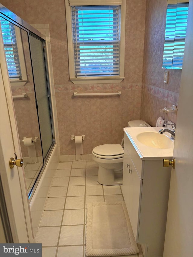 full bathroom featuring combined bath / shower with glass door, tile patterned floors, vanity, and toilet