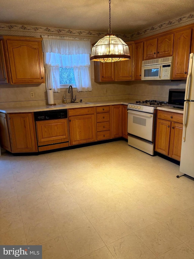 kitchen featuring pendant lighting, white appliances, sink, and a textured ceiling