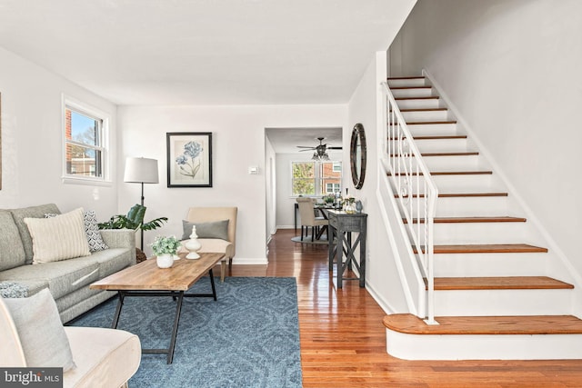 living room with baseboards, ceiling fan, stairs, and wood finished floors