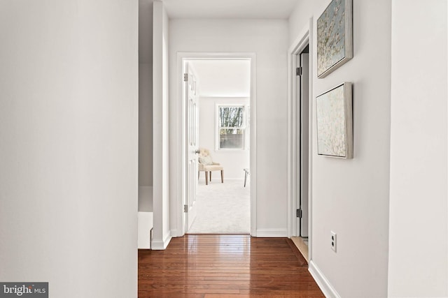 hallway featuring baseboards and dark wood-type flooring