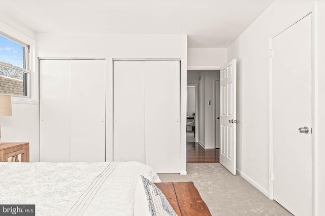 bedroom with multiple closets and light carpet