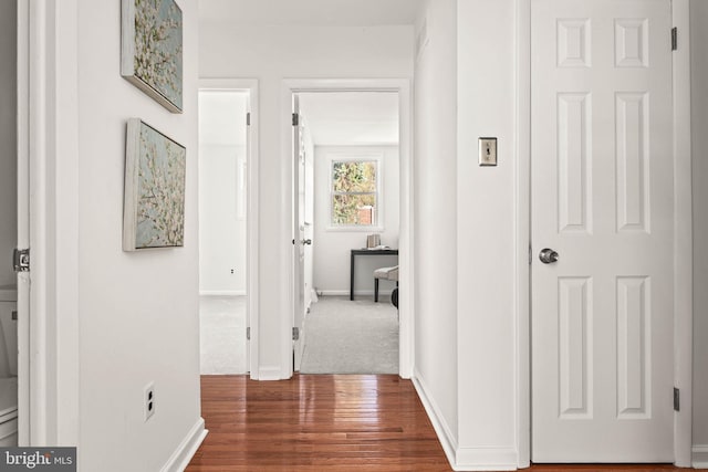 corridor with baseboards and wood finished floors