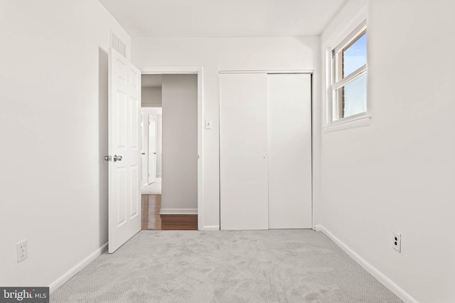 unfurnished bedroom with carpet floors, baseboards, visible vents, and a closet