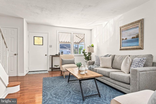 living room with baseboards, wood finished floors, and stairway