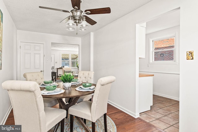 dining area featuring a ceiling fan, baseboards, wood finished floors, and a textured ceiling