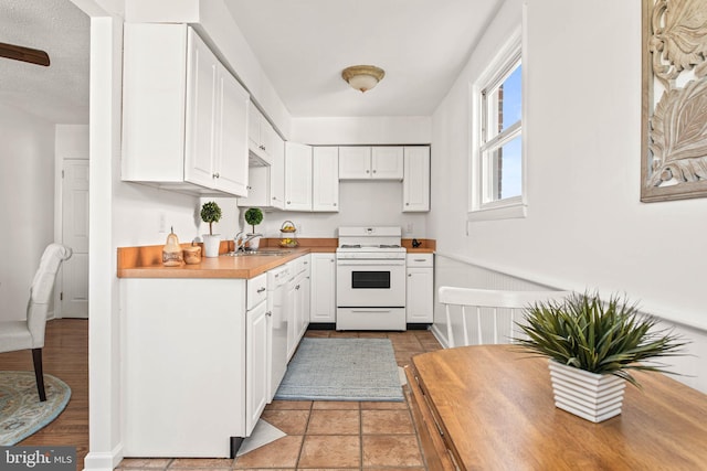 kitchen featuring a sink, white cabinets, white gas range, and light countertops