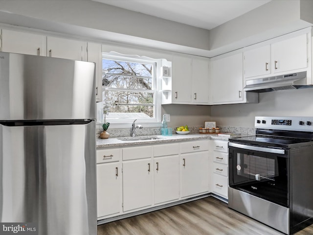 kitchen with sink, white cabinets, stainless steel appliances, and light hardwood / wood-style flooring