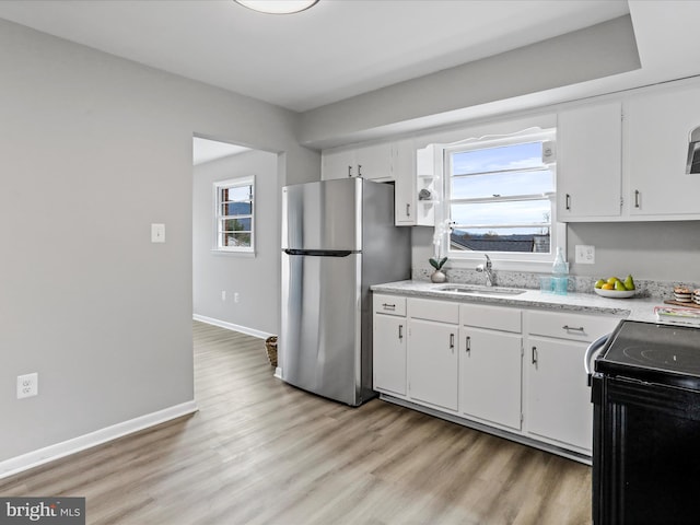 kitchen with stainless steel fridge, sink, white cabinets, and light wood-type flooring