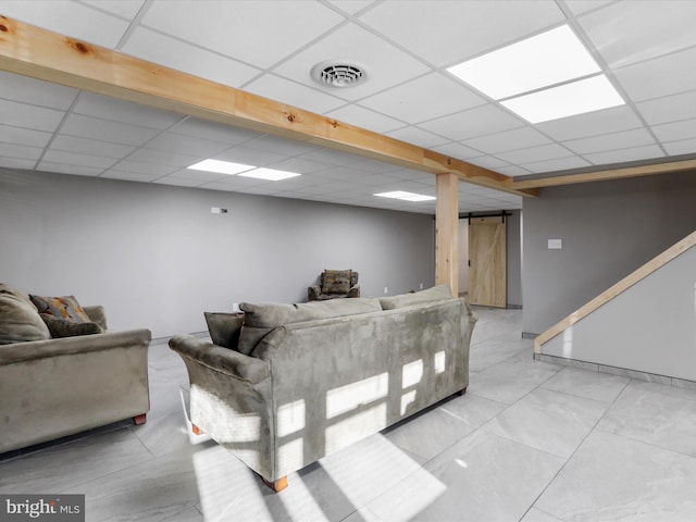 living room featuring a barn door and a drop ceiling