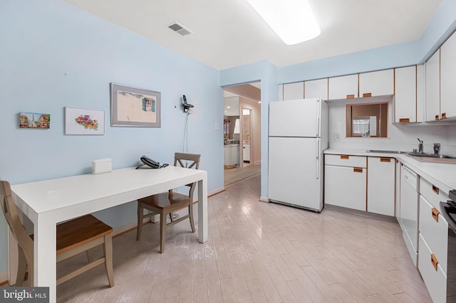 kitchen featuring sink, white cabinets, white appliances, and light hardwood / wood-style flooring