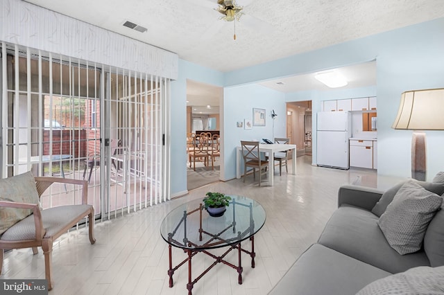 living room with ceiling fan and a textured ceiling