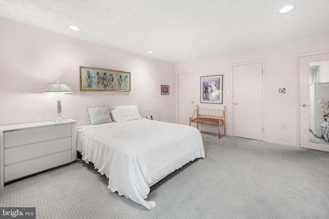 bedroom with light colored carpet and a textured ceiling