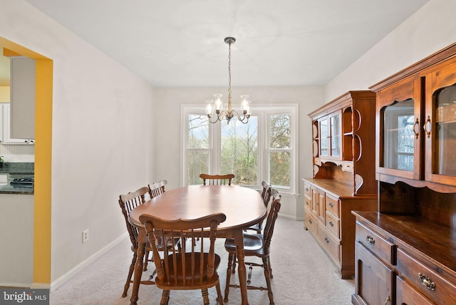 dining room with light carpet and a chandelier