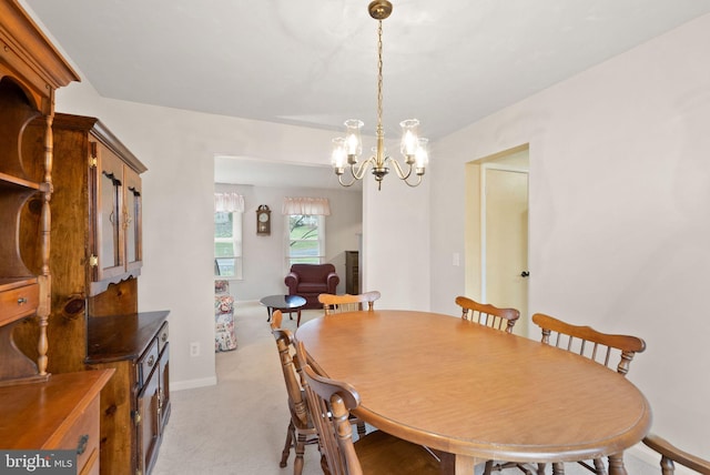 dining space featuring light colored carpet and a chandelier