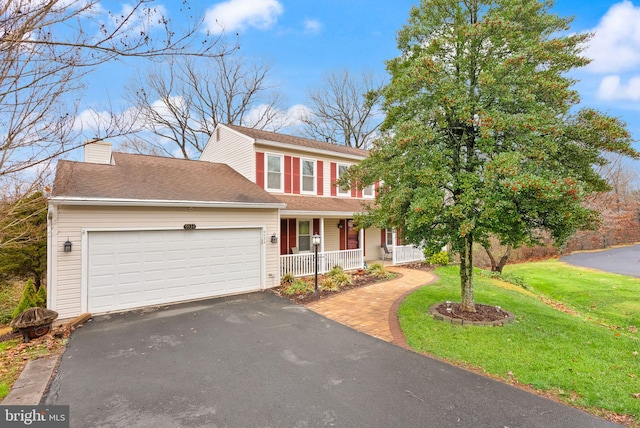 view of front of property featuring a porch, a garage, and a front lawn