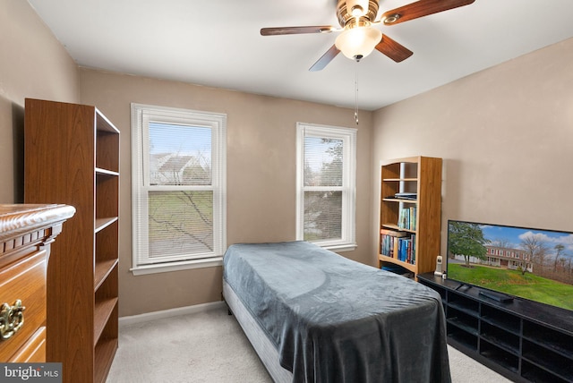 bedroom featuring ceiling fan, light colored carpet, and multiple windows