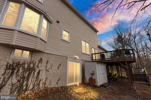 property exterior at dusk featuring a shed and a wooden deck