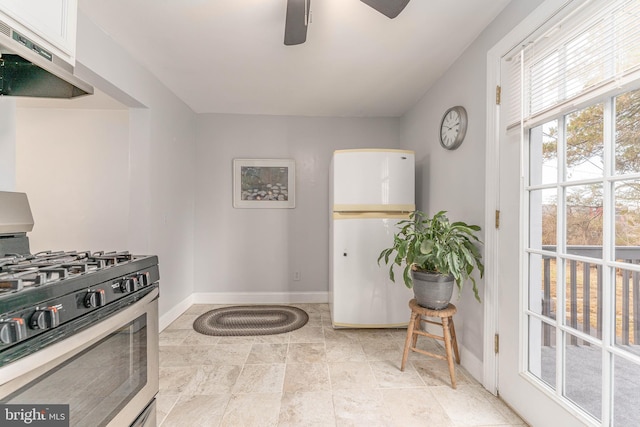 kitchen featuring stainless steel gas range oven, white fridge, white cabinetry, and exhaust hood