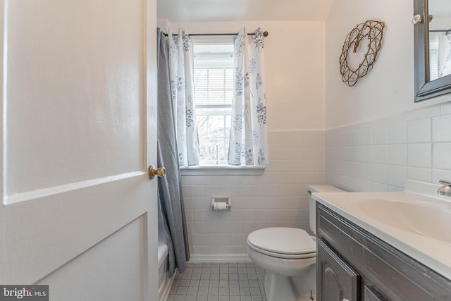 full bathroom featuring tile patterned floors, shower / bath combination with curtain, toilet, vanity, and tile walls