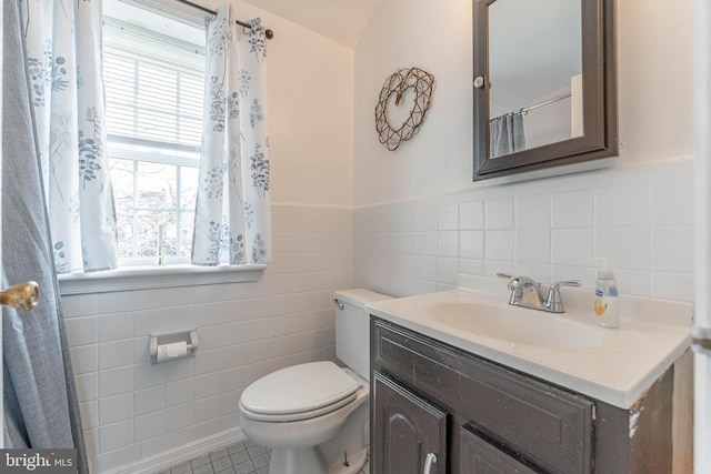 bathroom featuring tile patterned flooring, vanity, toilet, and tile walls