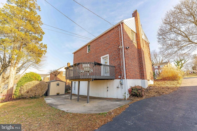 rear view of house with a storage unit, a patio, and a wooden deck