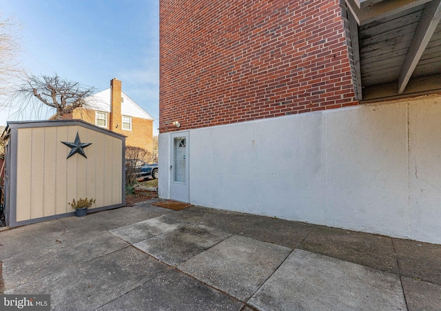 view of home's exterior with a storage shed and a patio area